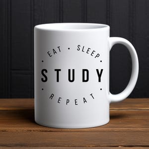 May include: White ceramic coffee mug with black text that reads "Eat. Sleep. Study. Repeat."