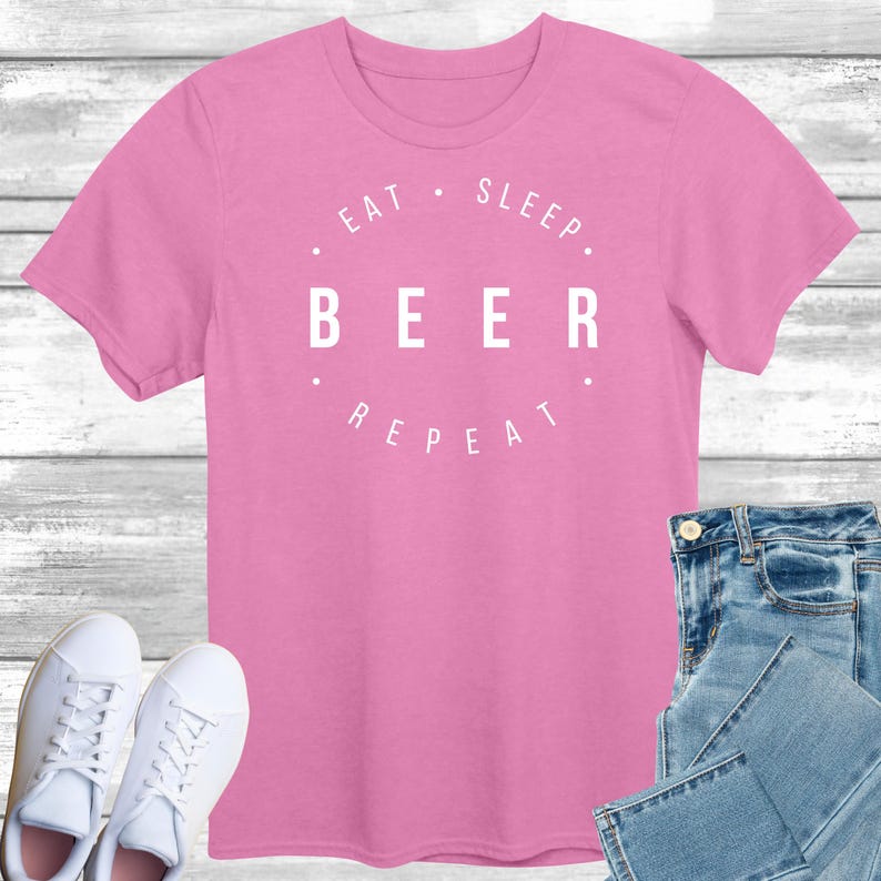 May include: Pink t-shirt with white text that reads "Eat. Sleep. Beer. Repeat."