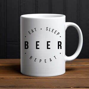 Peut inclure: Une tasse en céramique blanche avec du texte noir qui dit "Manger. Dormir. Bière. Répéter."