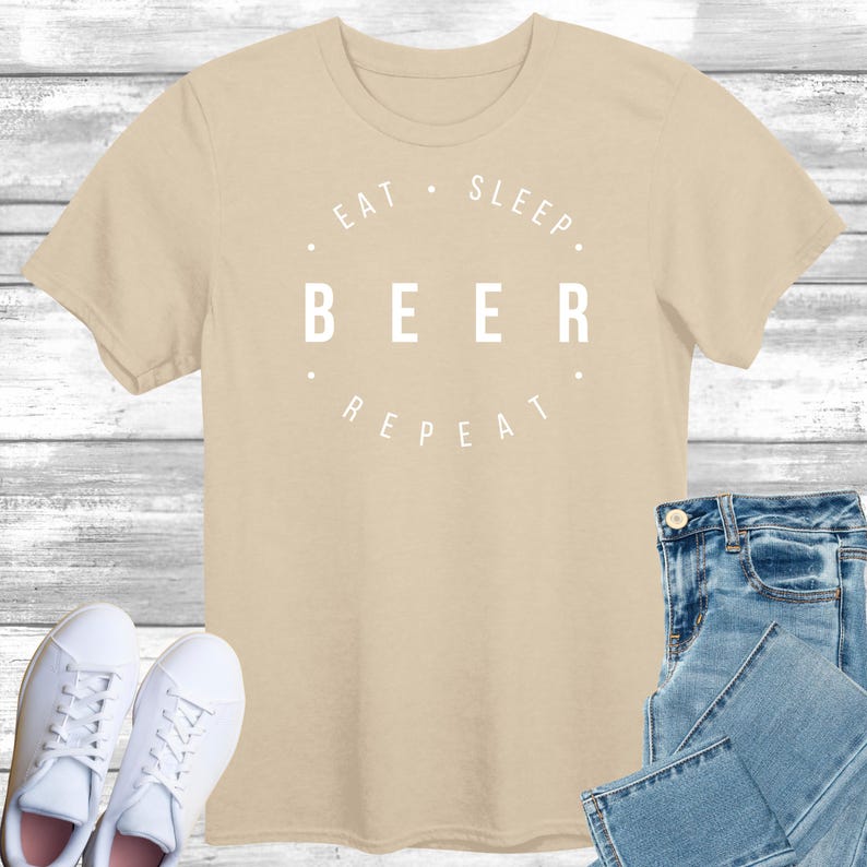 May include: A beige t-shirt with a white graphic that reads "Eat. Sleep. Beer. Repeat."
