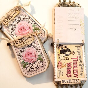 May include: A pink and white scrapbook with a floral design and the word "Darling" on the cover. The scrapbook is open to reveal a page with a vintage illustration of a game called "The Popular Game of Tiddledy Winks".
