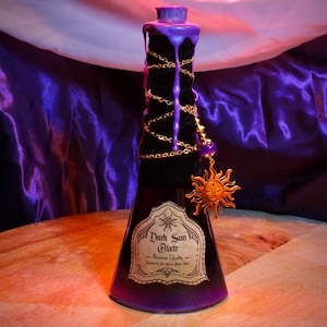 May include: A black potion bottle with a purple top and dripping accents. A gold chain with a sun charm and a purple bead hangs from the bottle. The label reads "Dark Sun Elixir - Premium Quality".