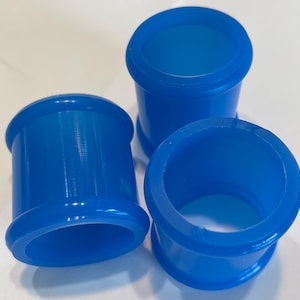 May include: Three vibrant blue cylindrical objects with a rounded top and bottom. The objects have a hollow center and a smooth, glossy finish. They are arranged in a group, showcasing their shape and color.