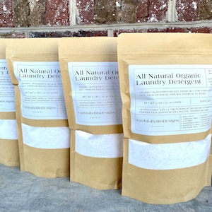 May include: Four brown paper bags filled with white laundry detergent powder. Each bag has a label that reads "All Natural Organic Laundry Detergent" with the ingredients listed and a net weight of 3 lbs (30-90 loads). The label also includes the company name "Faithfully His Designs" and the word "Organics".