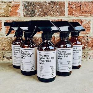 May include: Five amber glass spray bottles with black spray tops and white labels. The labels read "Organic Essential Oil Dryer Ball Mist" and "100% Organic, Non-Toxic, Multi-Purpose".