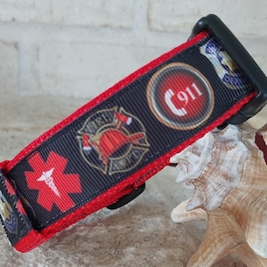 May include: Red, black and white dog collar with a firefighter, medical and 911 emblem. The collar has a black buckle.