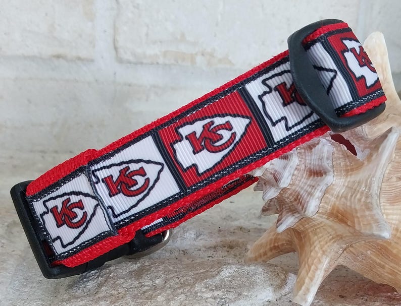 May include: Red, white and black dog collar with a repeating pattern of the Kansas City Chiefs logo. The collar has a black plastic buckle.