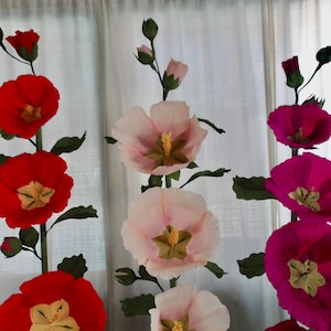 May include: Three paper flower arrangements, each with three flowers. The flowers are pink, red, and purple. The flowers are made of paper and have a realistic appearance.