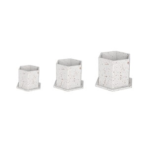 May include: Three white hexagonal ceramic planters with a speckled brown and white pattern. The planters are different sizes, with the largest planter in the back and the smallest planter in the front.