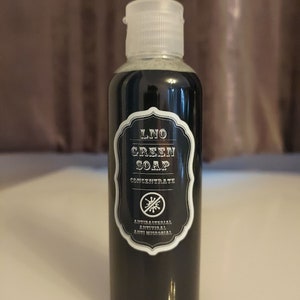 May include: A black bottle of LNO Green Soap Concentrate with a white label. The label has a black and white graphic of a no germs symbol and the text "Antibacterial, Antiviral, Anti Microbial".
