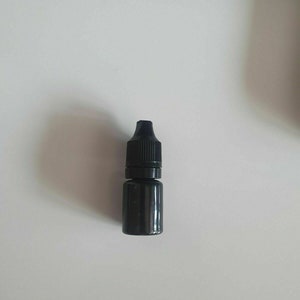May include: A small black plastic bottle with a dropper top.