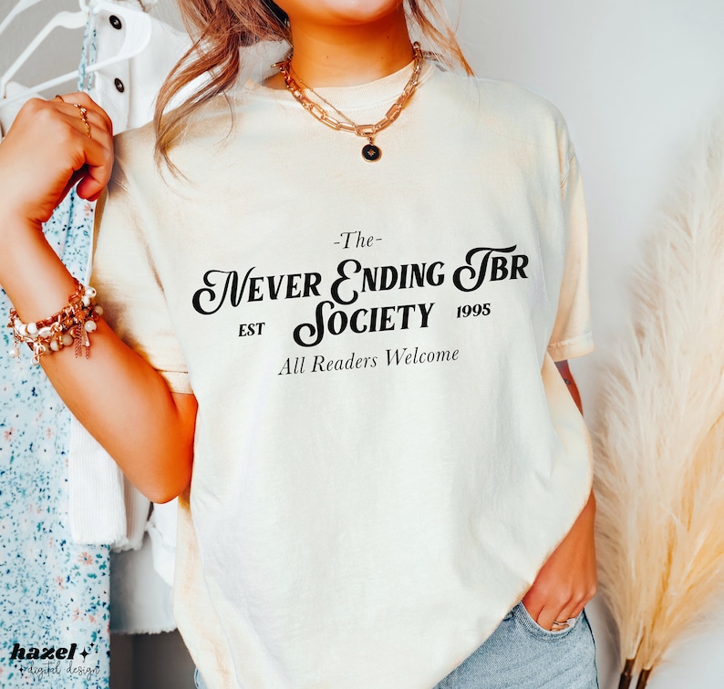 K&ouml;nnte beinhalten: Ein wei&szlig;es T-Shirt mit schwarzem Text, der "The Never Ending TBR Society Est 1995 All Readers Welcome" lautet.