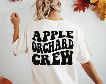 May include: White t-shirt with black text that reads "Apple Orchard Crew" in a retro font.