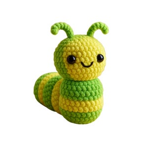 May include: A crocheted caterpillar toy in green and yellow. The caterpillar has a smiling face with black eyes and curved antennae. The body is segmented with alternating stripes of green and yellow yarn.