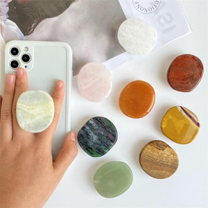 May include: Assortment of eight different coloured and patterned phone grips. The grips are made of natural stone and are shaped like circles. The grips are perfect for adding a touch of personality to your phone.