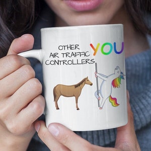 May include: White ceramic mug with a black and white illustration of a horse and a unicorn. The text on the mug reads "Other Air Traffic Controllers You".
