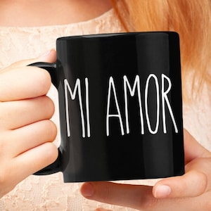 May include: A black ceramic mug with white text that reads "MI AMOR".