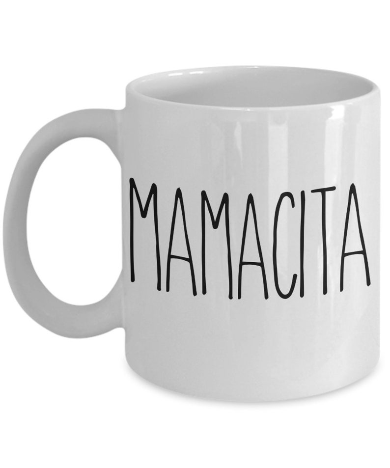 May include: White ceramic mug with the word "MAMACITA" printed in black, handwritten-style letters. The mug has a curved handle and a simple, clean design. A perfect gift for Mother's Day or any special occasion.