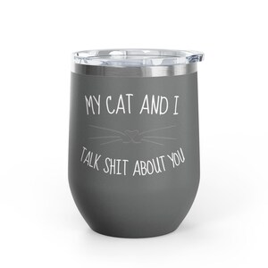 Op de afbeelding: Een grijze ge&iuml;soleerde tumbler met een doorzichtig deksel. De tumbler heeft de tekst "MY CAT AND I TALK SHIT ABOUT YOU" in het wit, met een kattengezicht. De tumbler is ontworpen om dranken warm of koud te houden.