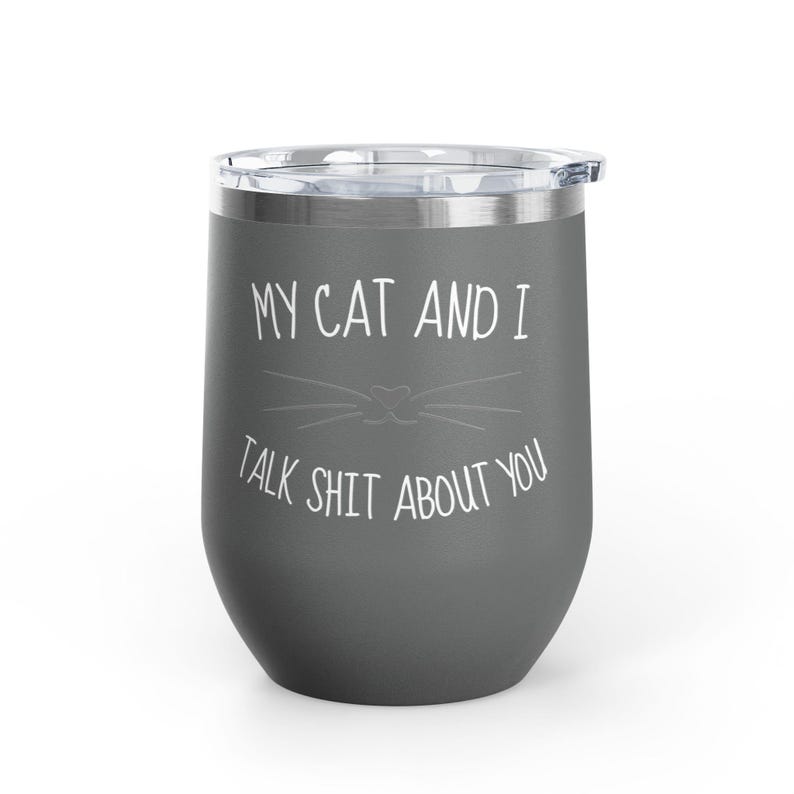 Op de afbeelding: Een grijze ge&iuml;soleerde tumbler met een doorzichtig deksel. De tumbler heeft de tekst "MY CAT AND I TALK SHIT ABOUT YOU" in het wit, met een kattengezicht. De tumbler is ontworpen om dranken warm of koud te houden.