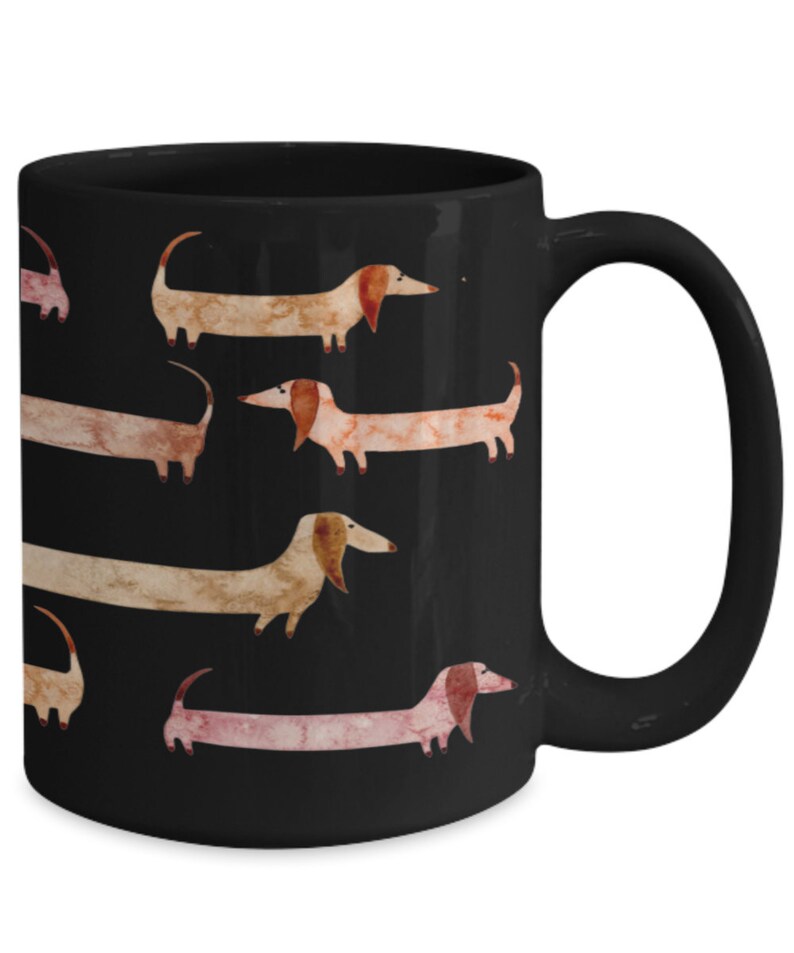 May include: Black ceramic mug featuring a repeating pattern of watercolor dachshunds in shades of brown, tan, and pink. The dogs have long bodies and floppy ears. The mug has a curved handle.