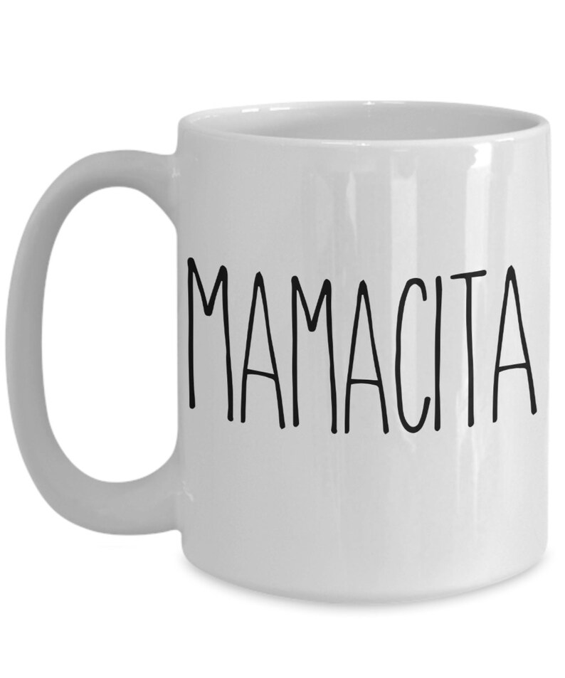 May include: White ceramic mug with the word "MAMACITA" printed in black, handwritten-style lettering. The mug has a curved handle and a glossy finish. A simple, everyday coffee mug.
