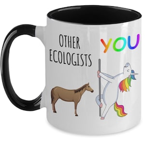 Può includere: Tazza in ceramica bianca con manico e interno neri. La tazza presenta il testo "OTHER ECOLOGISTS" e "YOU" in colori arcobaleno, insieme a illustrazioni di un cavallo e di un unicorno che fa pole dance.