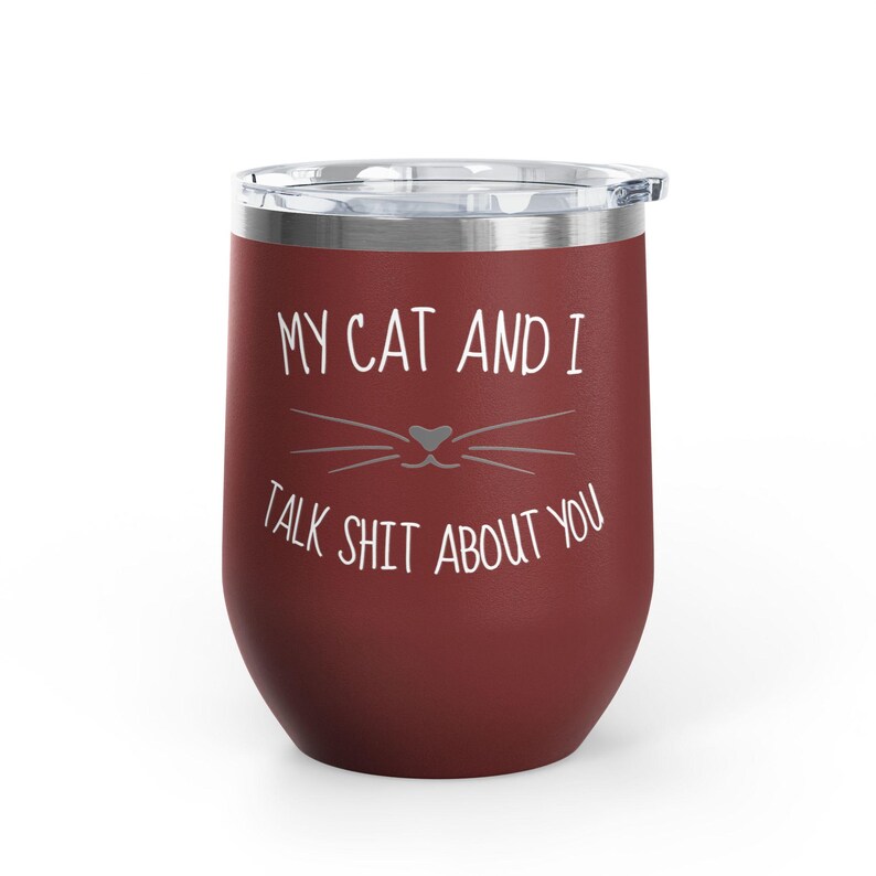 Op de afbeelding: Een bordeauxrode ge&iuml;soleerde wijnbeker met een doorzichtig deksel. De beker heeft witte tekst met de tekst "MY CAT AND I TALK SHIT ABOUT YOU" met een kattengezicht. Perfect voor kattenliefhebbers.