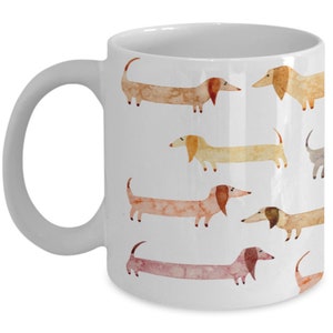 May include: White ceramic coffee mug with a pattern of watercolor dachshunds in various shades of brown, orange, and yellow.
