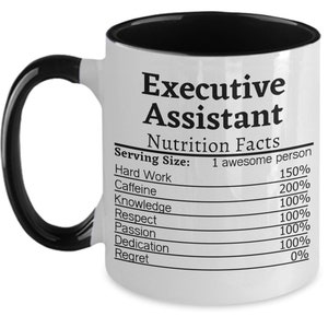 Op de afbeelding: Witte keramische mok met een zwarte handgreep en binnenkant. De mok heeft de tekst "Executive Assistant" en een "Nutrition Facts" label met humoristische percentages.