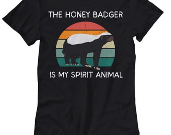 May include: Black t-shirt with a vintage-style graphic of a honey badger. The graphic features a sunset with a honey badger in the center. The text "The Honey Badger is my spirit animal" is printed below the graphic.