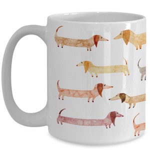 May include: White ceramic coffee mug with a pattern of watercolor dachshunds in various shades of brown, orange, and pink.