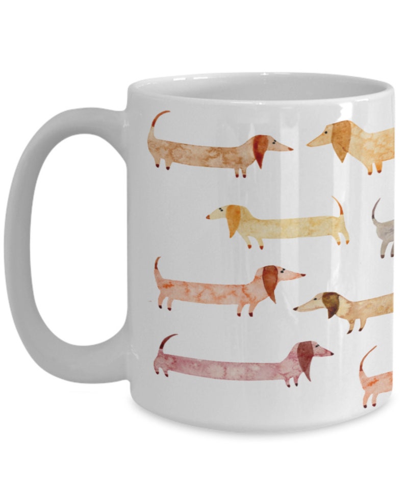 May include: White ceramic coffee mug with a pattern of watercolor dachshunds in various shades of brown, orange, and pink.