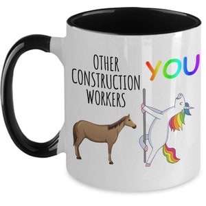 Puede incluir: Taza de café blanca con borde y asa negros. La taza tiene un gráfico de un unicornio con una crin y cola de arcoíris, sosteniendo un poste. El texto "OTHER CONSTRUCTION WORKERS" está en el lado izquierdo de la taza, y el texto "YOU" está en el lado derecho de la taza.