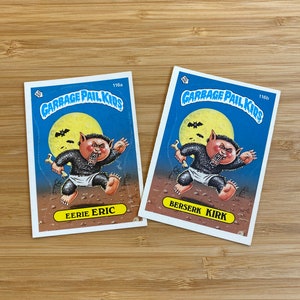May include: Two Garbage Pail Kids trading cards, featuring a werewolf-like character. The card on the left is titled "Eerie Eric" and the card on the right is titled "Berserk Kirk".