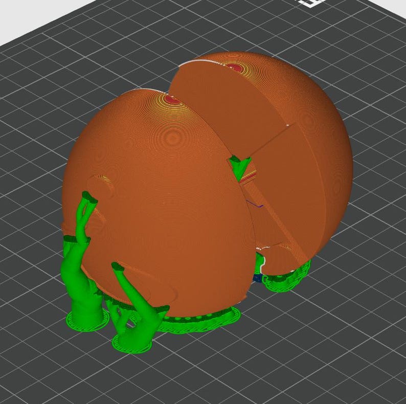 May include: A 3D printed object featuring a large, smooth, orange spherical shell divided into two main sections. The structure is supported by bright green, branching support struts that extend from the base to the exterior of the orange sphere.