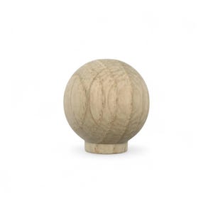 May include: A wooden ball knob with a light brown finish. The knob has a spherical shape with vertical grain lines and a small, cylindrical base. This decorative knob is suitable for furniture or cabinet projects.