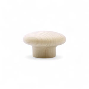 May include: A light-colored wooden cabinet knob with a mushroom-shaped top and a cylindrical base. The wood grain is visible on the surface. The knob is designed for furniture and cabinet hardware.