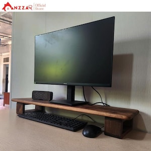 May include: A dark wooden monitor stand with a black computer monitor, keyboard, mouse, and digital clock. The stand has a rectangular shape with a raised platform for the monitor and a lower shelf for the keyboard.