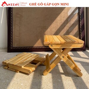 May include: A small, foldable wooden stool with a natural finish. The stool is made of light-colored wood and has a slatted seat. One stool is open, and another is folded flat. The text "GHẾ GỖ GẤP GỌN MINI" is visible.