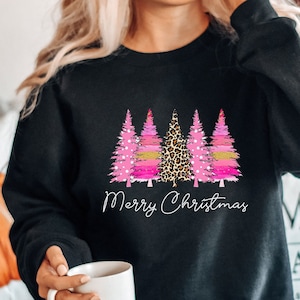 May include: Black sweatshirt with a pink and gold Christmas tree design and the text "Merry Christmas".