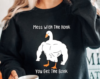 May include: A black sweatshirt with a white graphic of a muscular goose. The text on the sweatshirt reads "Mess with the Honk You Get the Bonk".