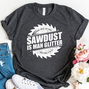 May include: A dark gray t-shirt with a white graphic of a saw blade that reads "Measure Twice Cut Once Sawdust Is Man Glitter Then Force It To Fit".