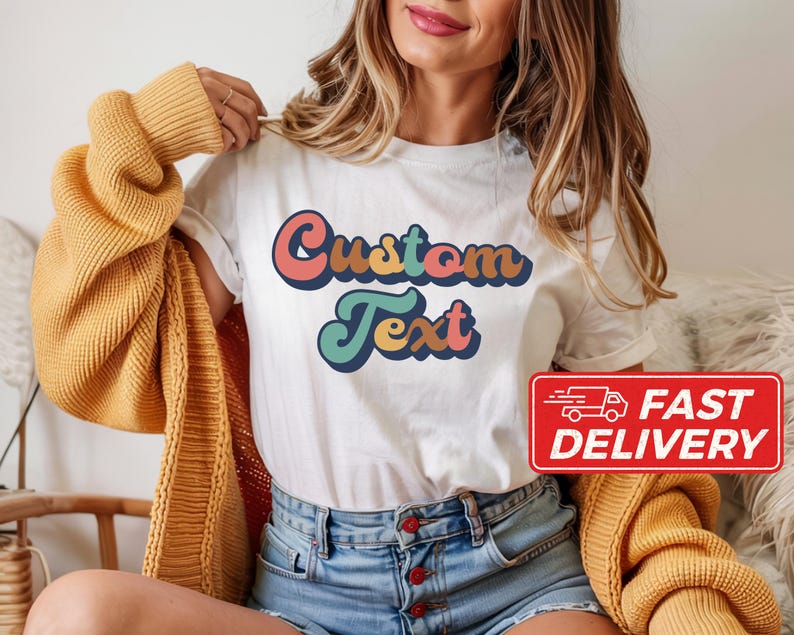 May include: White t-shirt with the words "Custom Text" in a retro font, featuring shades of pink, orange, teal, and blue. A red "Fast Delivery" sticker is visible. The shirt is part of a clothing collection.