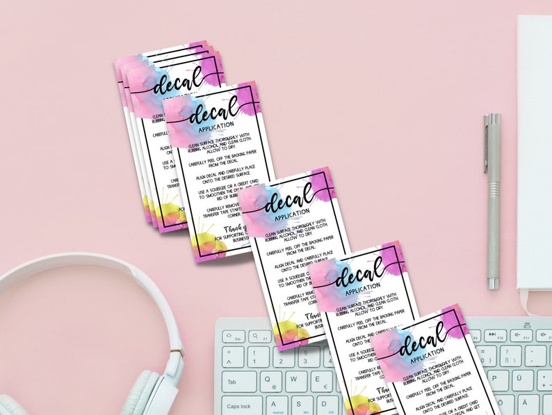 May include: A stack of five colorful cards with the word "decal" and "application" printed on them. The cards have a watercolor background with pink, blue, and yellow colors. The cards provide instructions on how to apply decals.