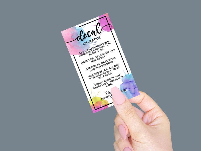 May include: A colorful card with watercolor splatter designs and instructions for applying a decal. The text reads "decal application" and includes steps for cleaning the surface, peeling the decal, and smoothing it out.