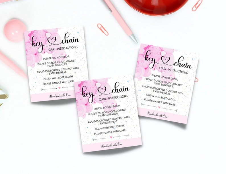 May include: Three pink and white key chain care instruction tags with a pink watercolor background and white glitter. The text on the tags reads "key chain" and "Care Instructions". The instructions include "Please do not drop", "Please do not knock against hard surfaces", "Avoid prolonged contact with extreme heat", "Clean with soft cloth", and "Please handle with care". The bottom of each tag reads "Handmade with Love".
