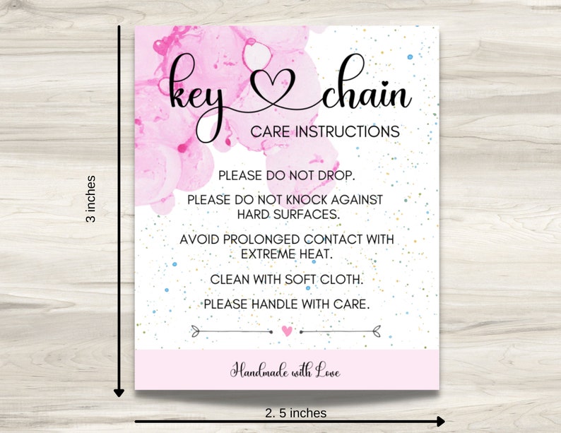 May include: Pink and white care instructions card for a key chain. The card has a pink watercolor background with gold and blue glitter. The text reads "key chain" with a heart symbol and "Care Instructions". The instructions are: "Please do not drop. Please do not knock against hard surfaces. Avoid prolonged contact with extreme heat. Clean with soft cloth. Please handle with care." The card also says "Handmade with Love".