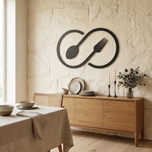 May include: A black metal wall art piece featuring a spoon and fork intertwined in an infinity symbol. The artwork hangs above a wooden sideboard with plates, candles, and a vase of flowers. The dining room has a neutral color palette.