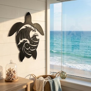 Peut inclure: Une œuvre d'art murale en métal noir en forme de tortue de mer avec un motif de vagues découpé au centre. L'œuvre est fixée sur un mur blanc avec des panneaux de bois horizontaux. Une cloche en verre avec des coquillages et un panier en osier sont au premier plan.